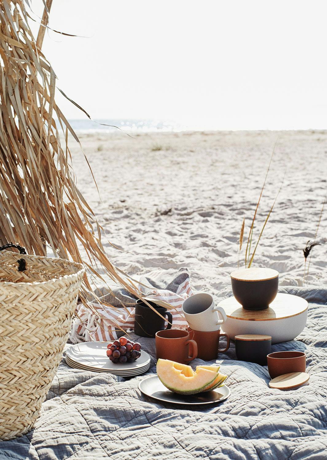 Nyt en frisk piknik på stranden Nydelig strandbilde med kopper og kar til en fin piknik